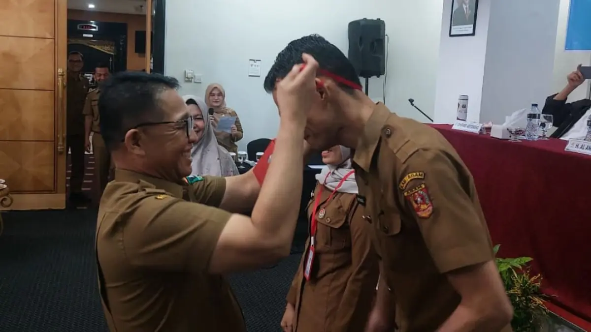 Al Amin, Kepala Bapenda Sumbar, mengalungkan tanda peserta kepada aparatur yang mengikuti Pelatihan Pemeriksa Pajak Daerah. Pelatihan berlangsung di Padang dengan menghadirkan narasumber dari Kementerian Keuangan.(Foto: Willian)