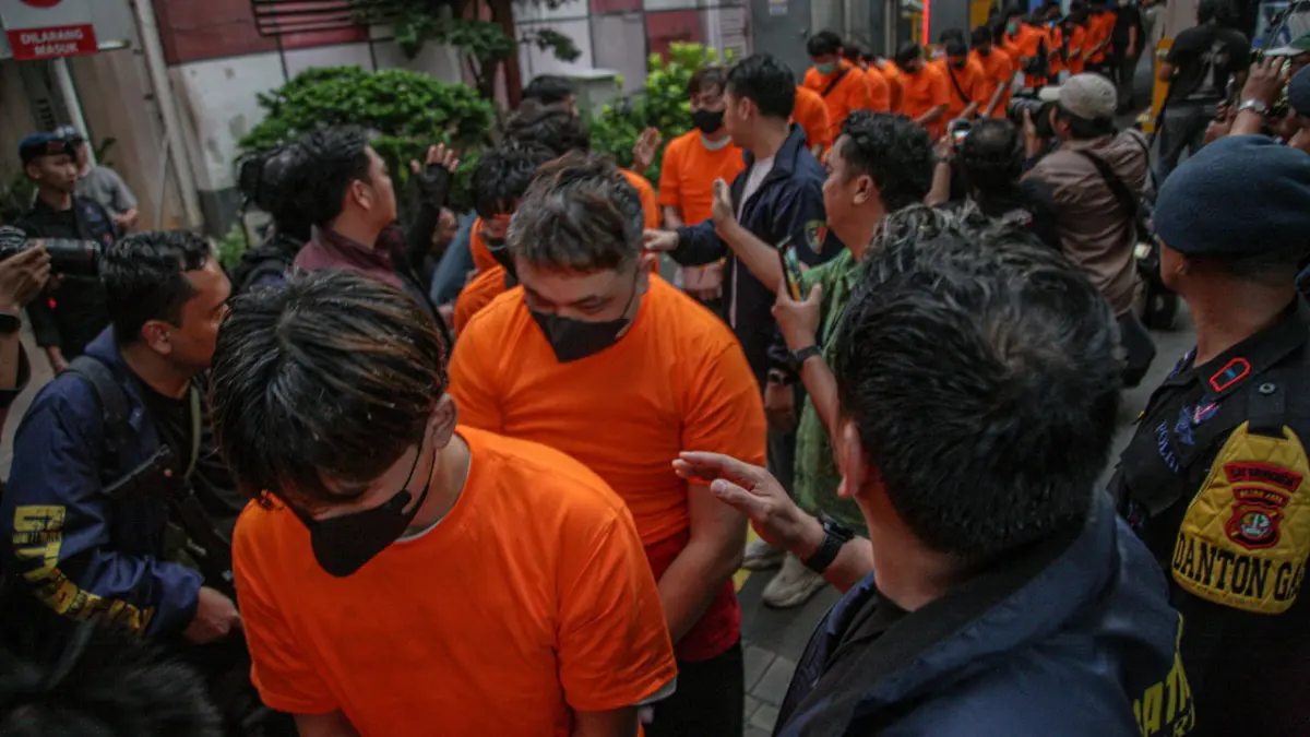 Sejumlah tersangka judi online dikawal ketat oleh aparat kepolisian keluar dari Hayam Wuruk Tower, Jakarta, Minggu (10/5). (HANUNG HAMBARA/JPG)
