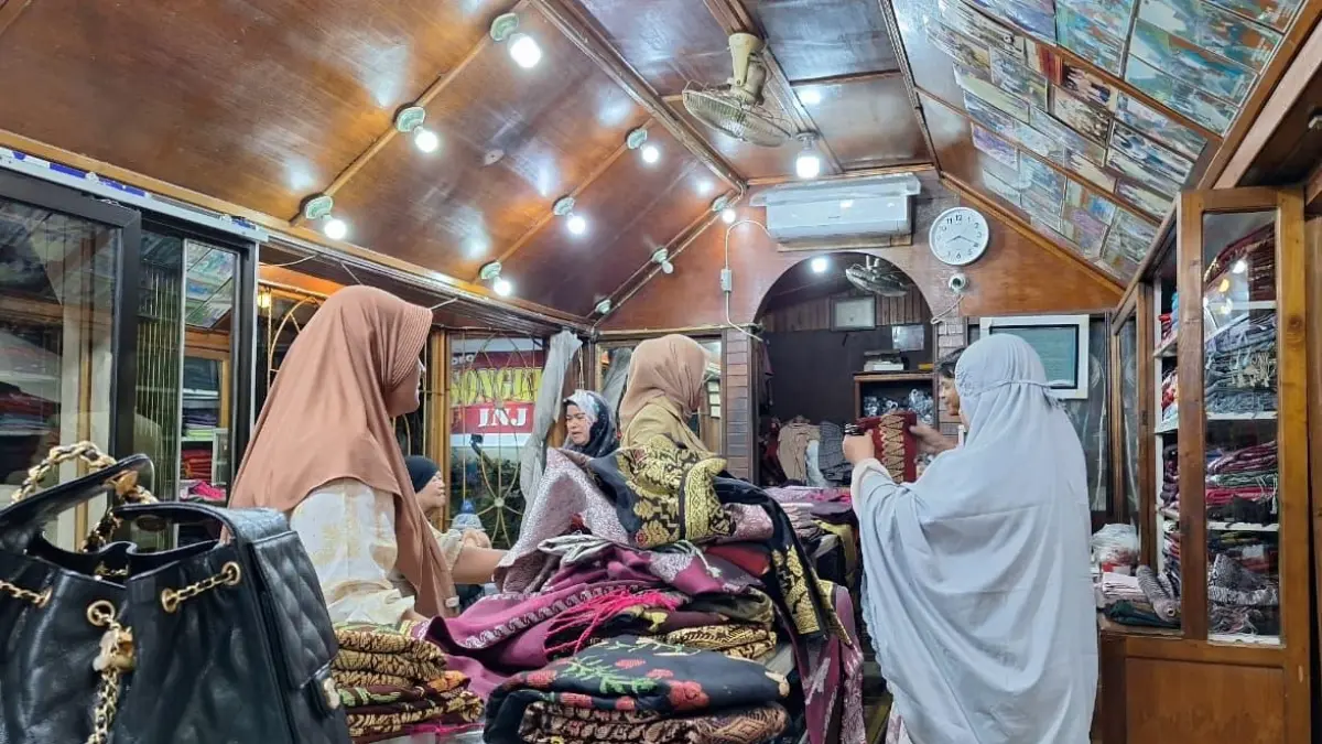 Rita Kurnia, pemilik galeri INJ Songket Silungkang, menunjukkan koleksi songket di galerinya di Desa Silungkang Tigo, Sawahlunto. Di tengah tingginya permintaan pasar, pelaku usaha songket justru kesulitan mencari perajin karena banyak penenun beralih menjadi pendulang emas ilegal. (INDRA YOSEF/PADEK)