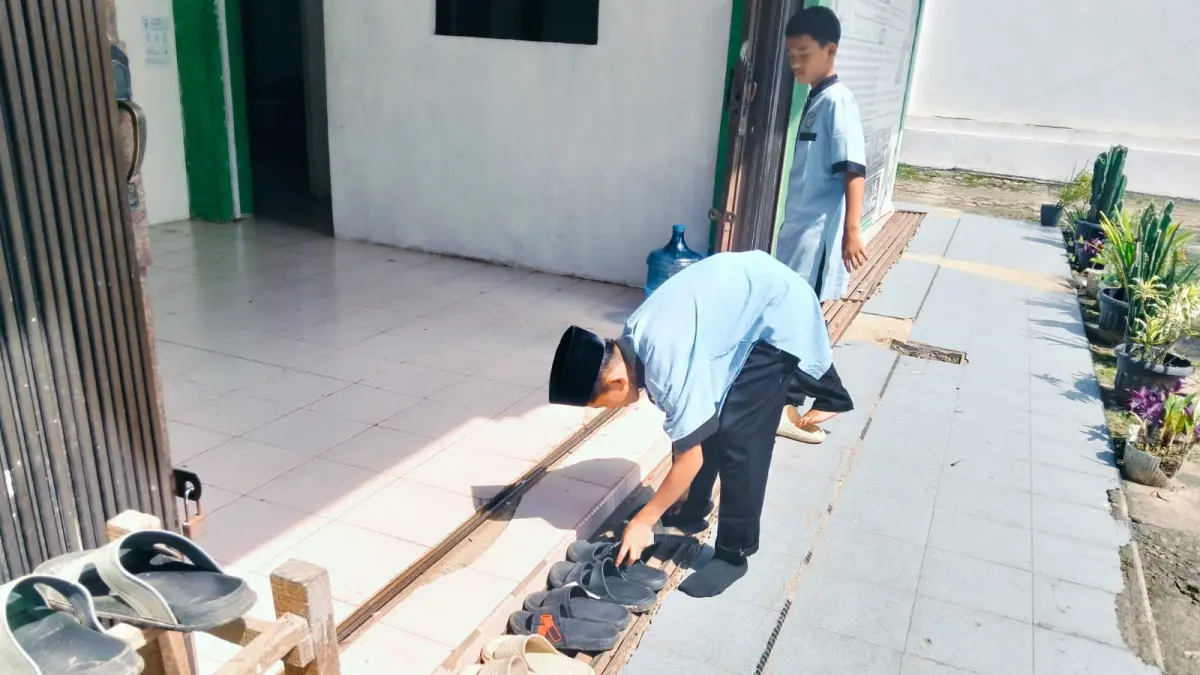 Seorang  siswa SMP Al Furqon Kotobaru Simalanggang menyusun sepatu dan sandal bagian dari nilai-nilai kehidupan yang ditanamkan di sekolah tersebut. (TIM LAMAN GURU)