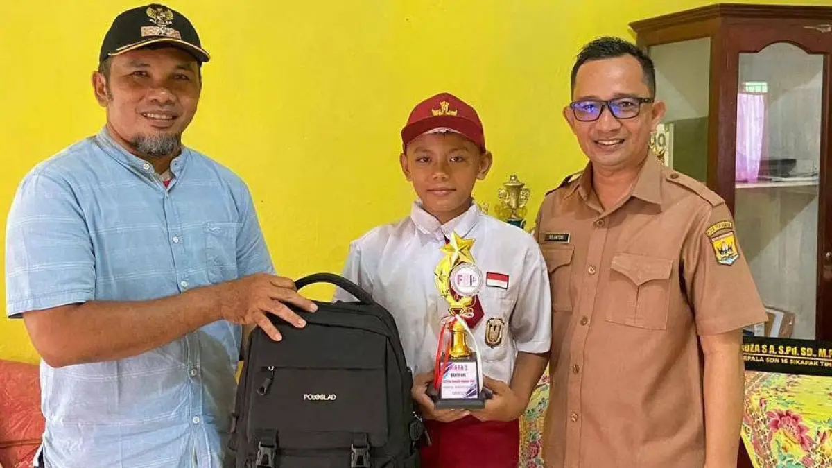 Kepala Desa Syawirman, S.Kom. didampingi kepala sekolah memberikan bantuan  perlengkapan sekolah pada siswa berprestasi di SDN 16 Sikapak Timur beberapa waktu lalu. (TIM LAMAN GURU)