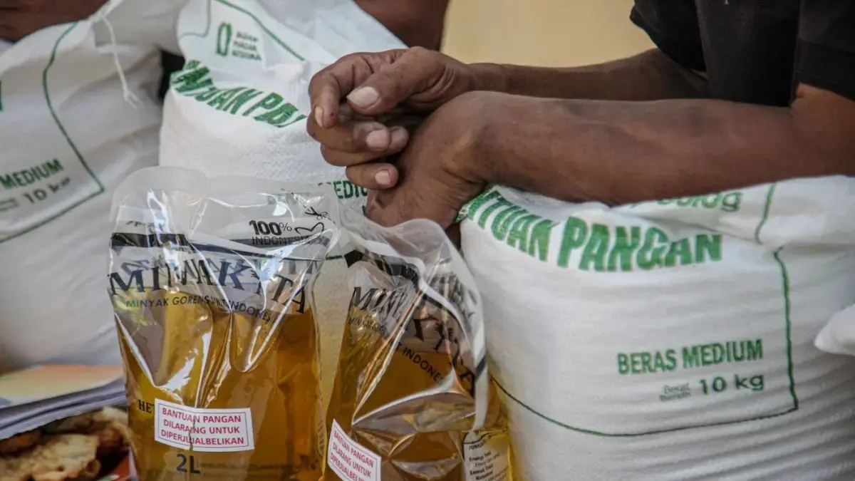 Warga penerima bantuan pangan membawa sejumlah bantuan berupa beras dan minyak goreng saat penyaluran bantuan Keluarga Penerima Manfaat (KPM) di Kantor Kelurahan Batusari, Kota Tangerang, Kamis (14/5). (Hanung Hambara/Jawa Pos)