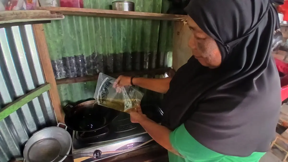 Salah seorang pedagang menggunakan Minyakita untuk memasak dagangannya, Selasa (9/6). (SUYUDI/PADEK)