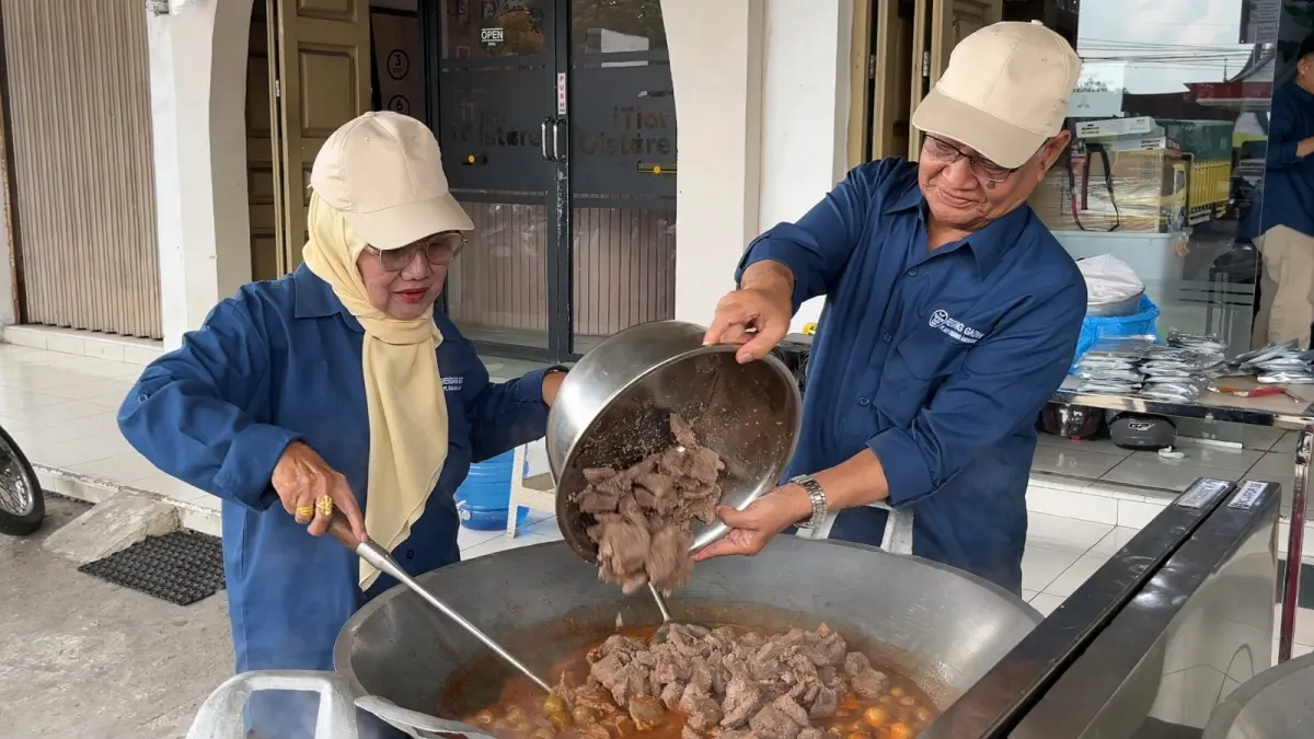 MASAK RENDANG: Komisaris PT Gadih Minang Anugerah, Syafruddin bersama Anwida memasukkan daging ke kuali saat kegiatan Masak Besar Rendang Gadih di Payakumbuh, Jumat (12/6). Sebanyak 700 porsi rendang dibagikan gratis kepada masyarakat. (Dok. Rendang Gadih)