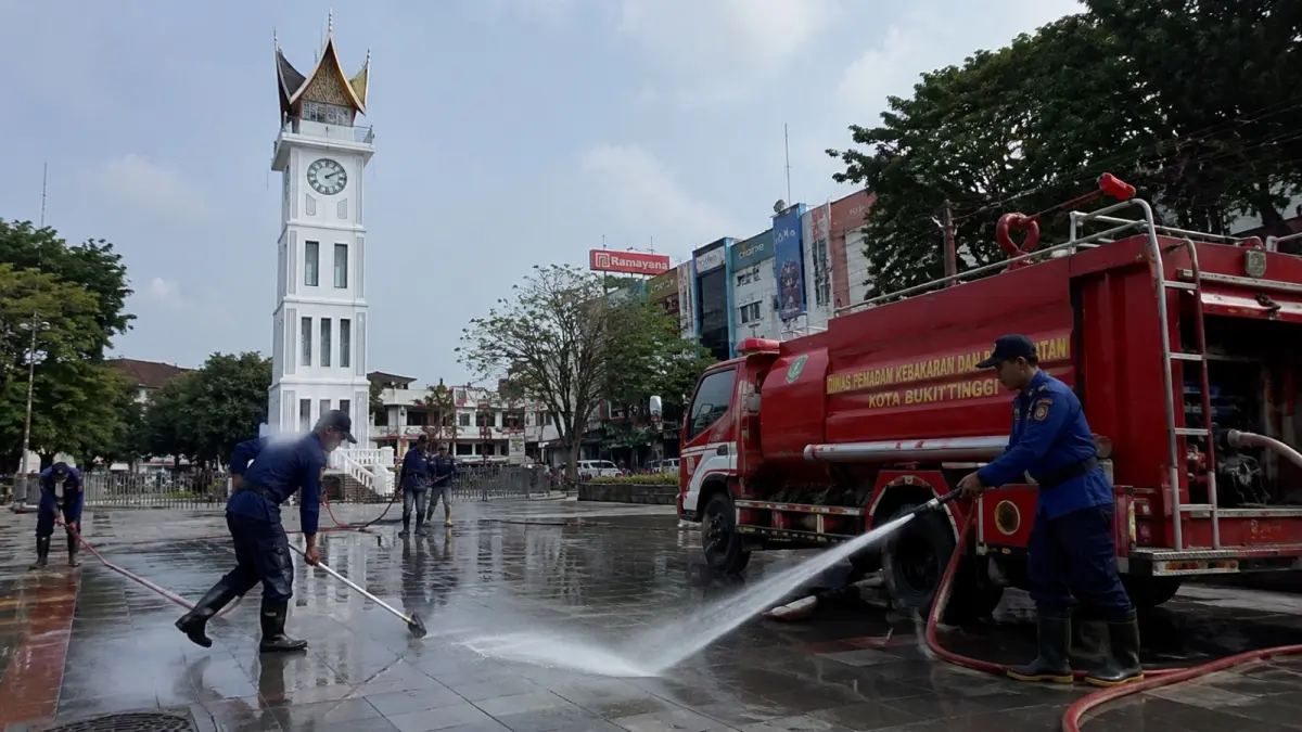 Petugas DPKP Kota Bukittinggi melakukan penyiraman dan pembersihan di kawasan Jam Gadang, Pasar Atas, dan Janjang Gudang, Selasa (16/6/2026). Kegiatan ini bertujuan menjaga kebersihan lingkungan sekaligus meningkatkan kenyamanan wisatawan yang berkunjung ke pusat kota. (Ilustrasi AI)