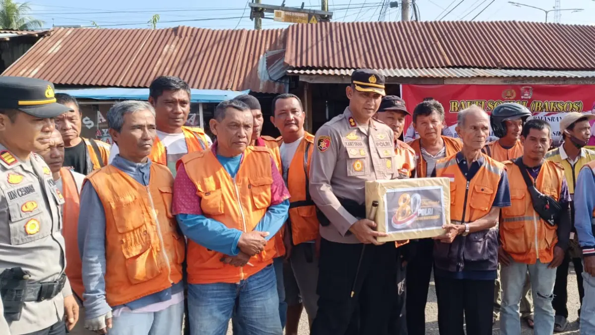 Kapolres Dharmasraya AKBP Kartyana Widyarso Wardoyo Putro menyerahkan bantuan sembako kepada komunitas ojek di Pasar Baru Pulau Punjung dalam rangka peringatan Hari Bhayangkara ke-80, Jumat (19/6/2026).