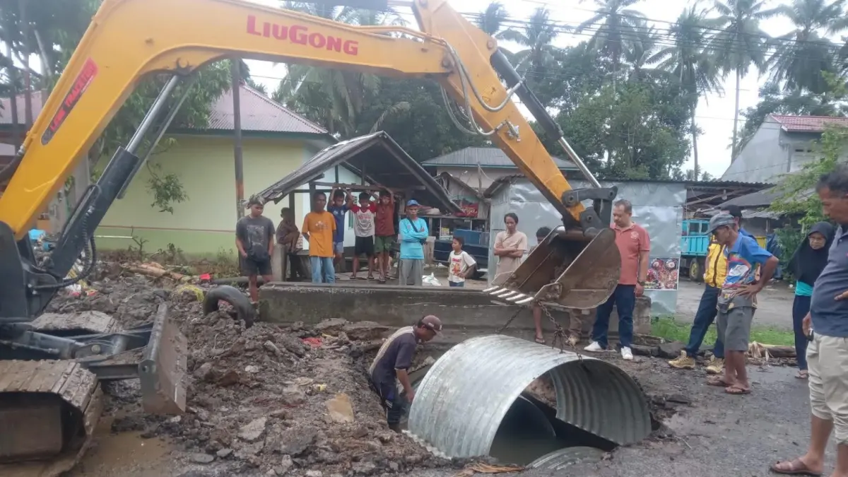 Alat berat melakukan pemasangan gorong-gorong baja bergelombang (Armco) pada ruas jalan Balai Salasa, Kecamatan Lubukbasung, yang amblas akibat kerusakan saluran drainase, Senin (22/6). Penanganan sementara dilakukan untuk memulihkan akses lalu lintas dan menjamin keselamatan pengguna jalan sembari menunggu perbaikan permanen yang dijadwalkan mulai Juli 2026. (PEMKAB AGAM)