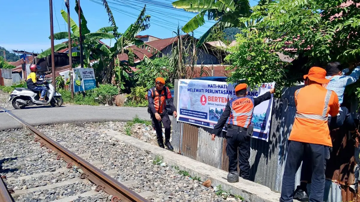 Petugas KAI Divre II Sumbar memasang spanduk keselamatan di perlintasan sebidang sebagai upaya menekan risiko kecelakaan selama masa libur sekolah.