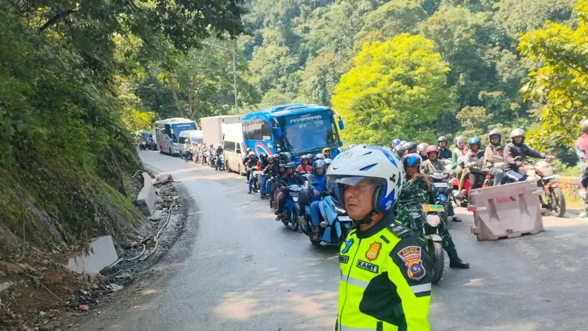 Petugas Satlantas Polres Padangpanjang mengatur arus lalu lintas saat sistem buka tutup diberlakukan di KM 66+700 Lembah Anai akibat proses pembersihan material bekas longsor, Senin (29/6/2026).&nbsp;