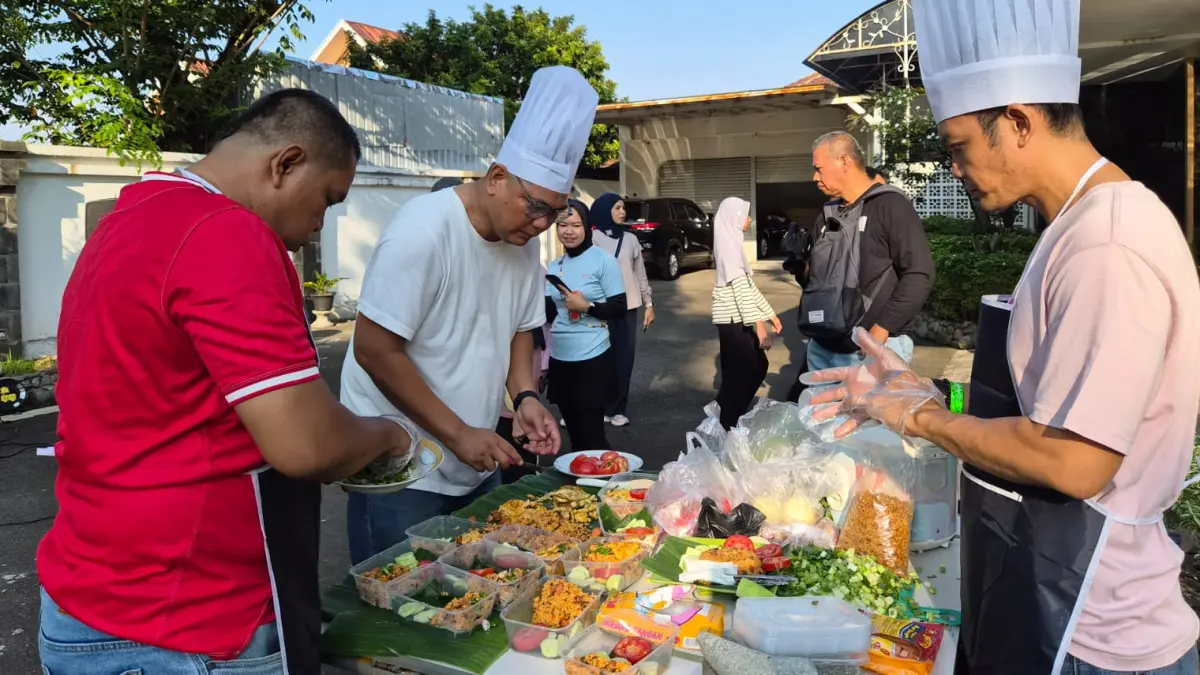 Wartawan peserta lomba memasak nasi goreng mempersiapkan hidangan yang akan dijual kepada masyarakat saat Car Free Day di depan rumah dinas Kepala Bank Indonesia Sumbar, Minggu (5/7/2026). Seluruh transaksi menggunakan QRIS dalam rangka memeriahkan HUT ke-73 Bank Indonesia.