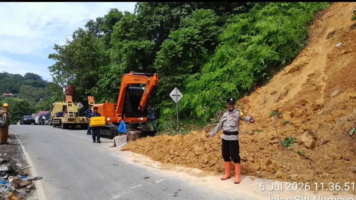 Petugas DPUPR Kota Padang mengoperasikan alat berat untuk membersihkan material longsor yang menutup sebagian badan jalan di kawasan Gunung Padang, Kelurahan Batang Arau.(Foto: Diskominfo)
