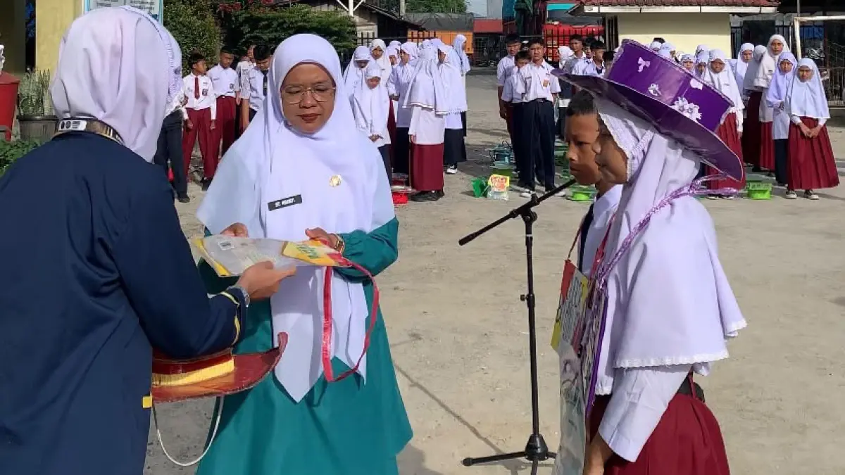 Kepala Sekolah sedang memasang atribut MPLS kepada siswa SMPN 2 Bukittinggi, Senin (13/7). (TIM LAMAN GURU)