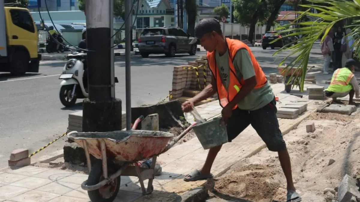 Pekerja memperbaiki trotoar sebagai bagian program Padang Rancak untuk pejalan kaki yang lebih aman.(Foto: Diskominfo)
