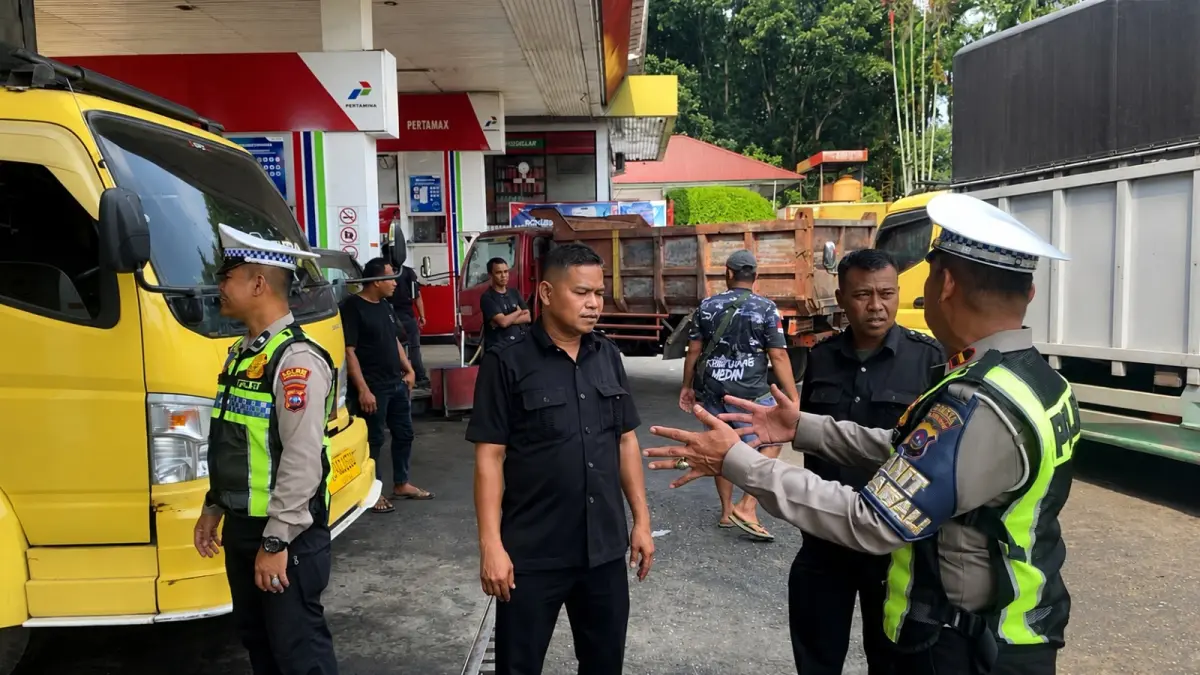 Personel Satlantas Polres Dharmasraya melakukan pengaturan lalu lintas di salah satu SPBU untuk mengantisipasi kemacetan akibat antrean truk pengisi BBM di Jalan Lintas Sumatera.