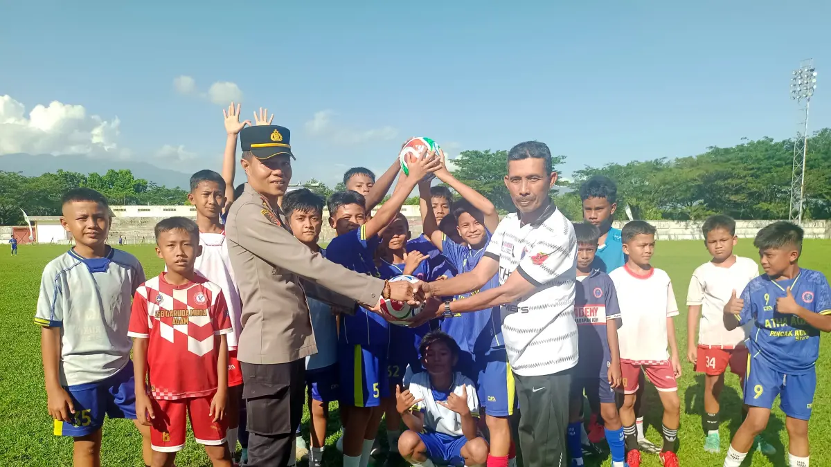 PEMBINAAN USIA DINI: Wakapolsek Lubuk Basung IPDA Riqul Mukhtadi menyerahkan bantuan dua bola kaki kepada Pelatih SSB Academy Tunas Harapan Agam, Beni Sastra, disaksikan para pemain di Stadion Bukit Bunian, Lubuk Basung, Kamis (23/7).