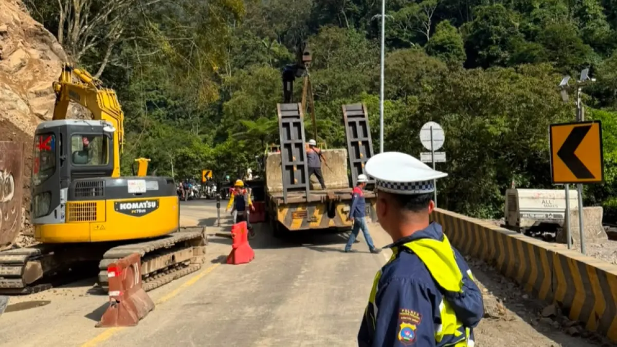 Petugas Satlantas Polres Padangpanjang mengatur arus kendaraan di Jalan Padang-Bukittinggi KM 66.700 kawasan Lembah Anai saat pembersihan material longsor, Jumat (31/7/2026).