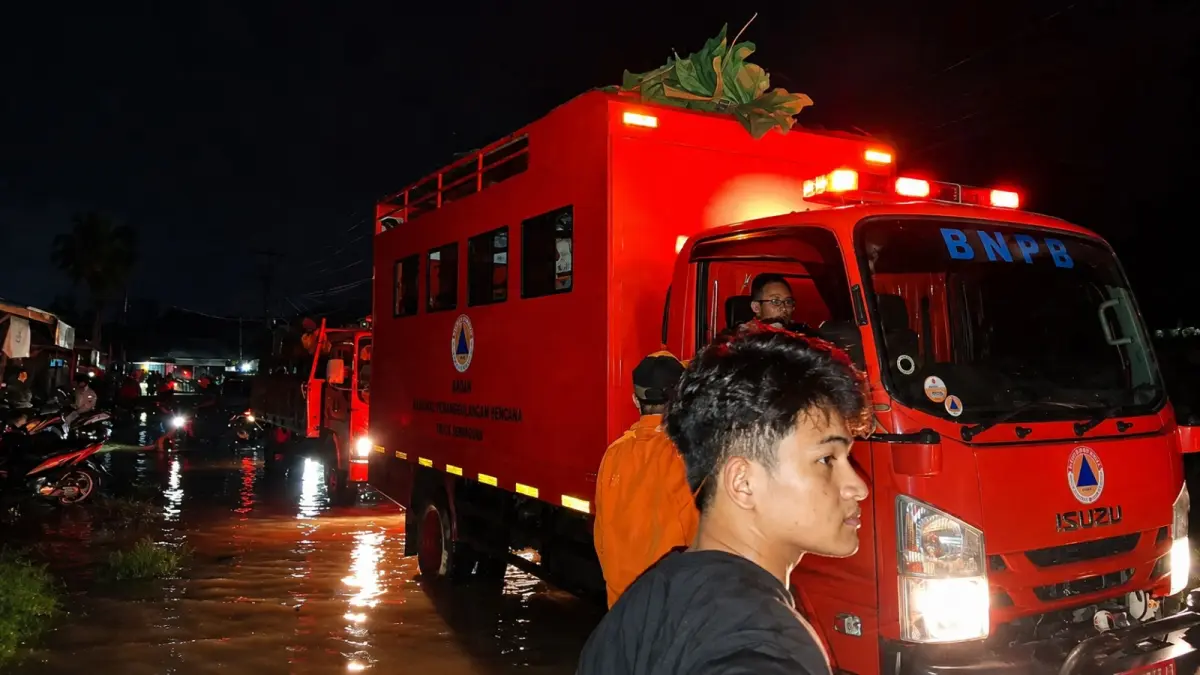 Tim penanggulangan bencana bersiaga menggunakan kendaraan operasional di tengah genangan air pada malam hari menyusul hujan deras di wilayah terdampak, Senin (3/8/2026).