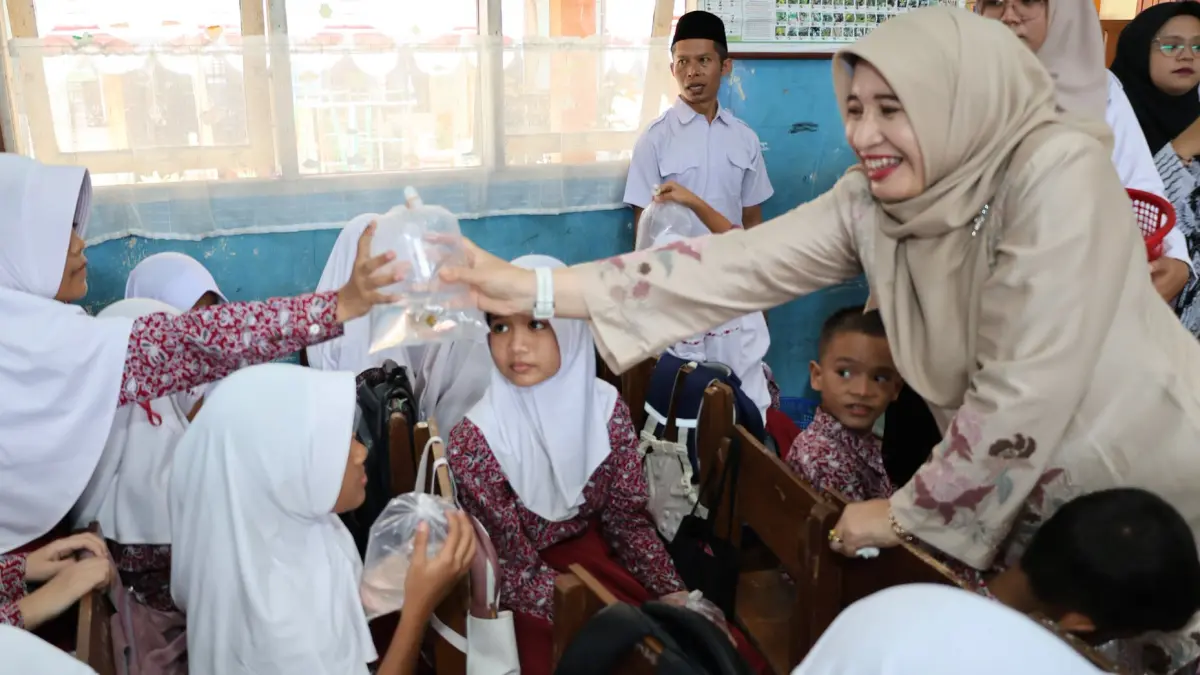 Ny. Yosneldi Balad menyerahkan bibit ikan koi kepada siswa sekolah dasar di Kota Pariaman, Rabu (5/8/2026).