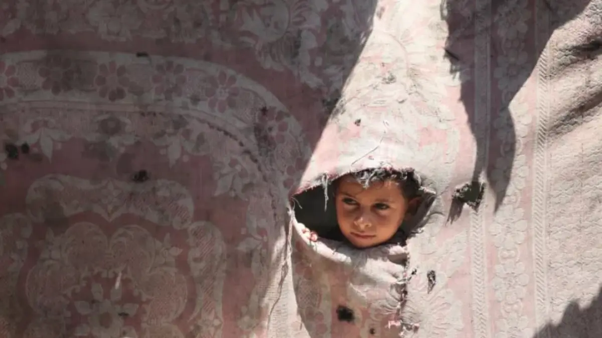 Jasser, seorang anak berusia 7 tahun dari Gaza, melihat keluar dari salah satu dinding tenda yang rusak. (Foto: UNICEF/Eyad El Baba)