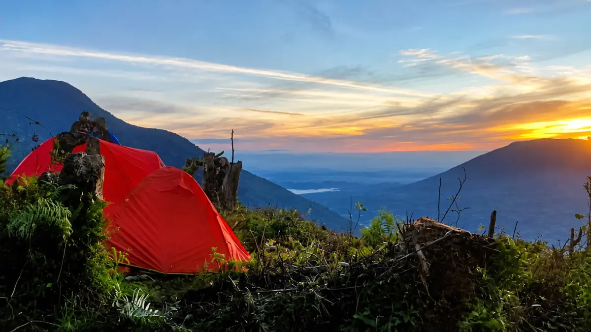 Tenda tim ekspedisi berdiri di kawasan puncak Tandikek 2.438 Mdpl, dengan panorama pegunungan dan matahari terbit (sunrise) yang menyinari langit di balik puncak Marapi. (Two Efly/Padeks)