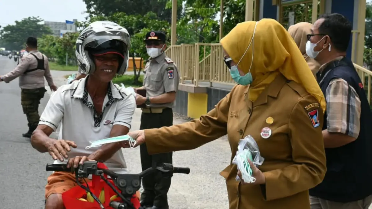 Petugas BPBD Padang membagikan masker kepada pengguna jalan. (Foto: Diskominfo)