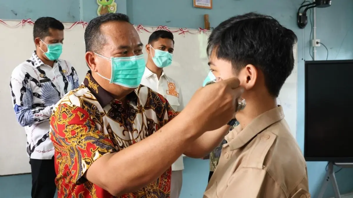 Wali Kota Pariaman Yota Balad memasangkan masker kepada pelajar untuk mengantisipasi dampak kabut asap, Kamis (10/9/2026).