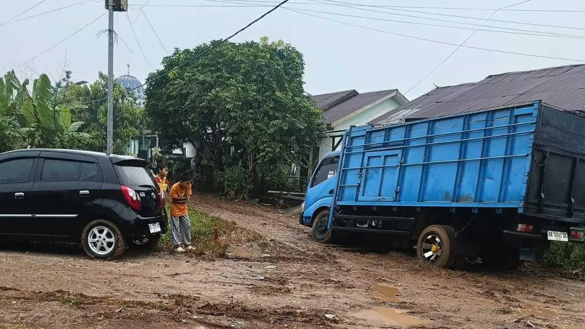 Truk terperosok di jalan Perumahan Rabah Tibarau, Dharmasraya, yang berubah menjadi kubangan lumpur setelah penggalian pipa PDAM.