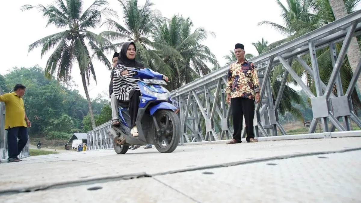 Seorang ibu pengendara sepeda motor melintas di Jembatan Bailey Titian Putiah, Nagari Taluak, Kecamatan Lintau Buo, Tanahdatar.