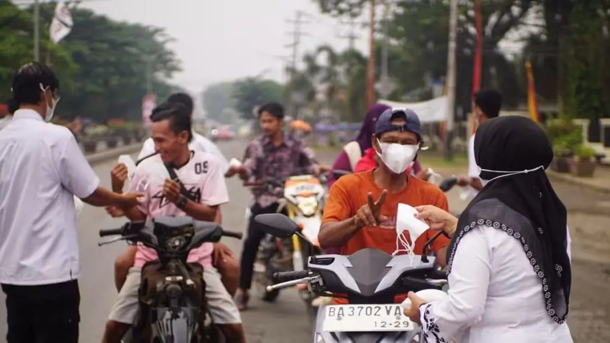 Petugas Dinas Kesehatan membagikan masker kepada pengendara sebagai upaya mengurangi paparan kabut asap di Dharmasraya, Senin (5/10/2026).