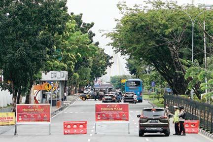 Petugas kepolisian berjaga saat rekayasa lalu lintas dengan mengalihkan arus kendaraan yang akan melewati Jalan Jenderal Sudirman,Pekanbaru, kemarin (27/4). Pengalihan arus ini membatasi gerak masyarakat pada penerapan PSBB di Kota Pekanbaru. Hal sama jug