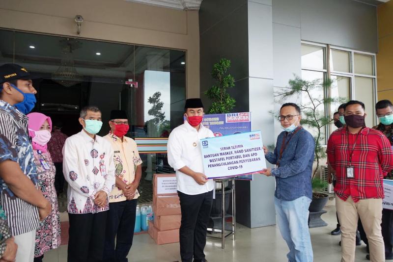 Pinca BRI Dharmasraya Devi Ridwan serahkan bantuan APD kepada Bupati Dharmasraya Sutan Riska Tuanku Kerajaan. (Foto: Ita)