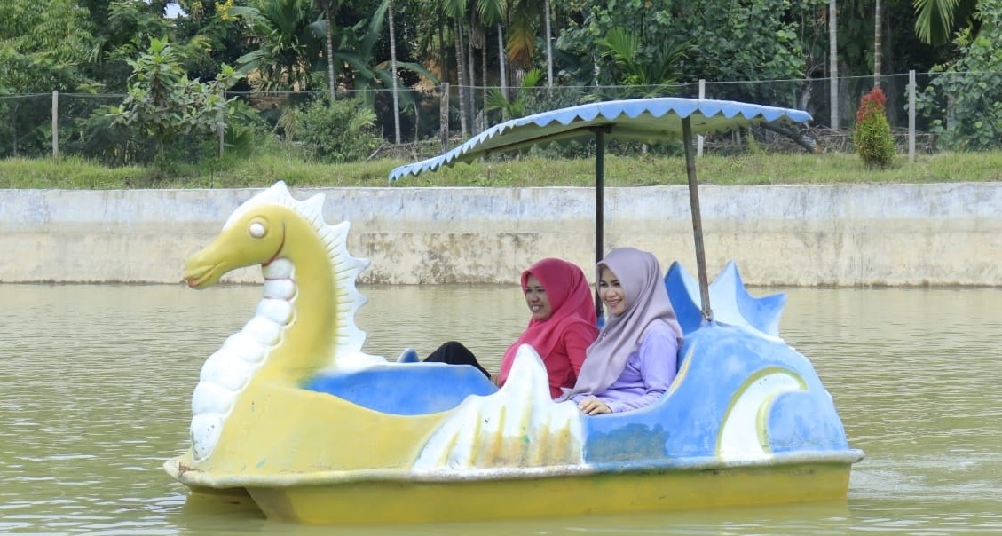 Ny Dewi Sutan Riska begitu menikmati wahana perahu dayung hias di Gunung Sari, Koto Besar, Dharmasraya.