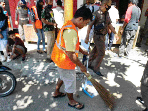 Pelanggar Perda AKB yang  terjaring razia menjalani  sanksi sosial membersihkan pasar. (IST)