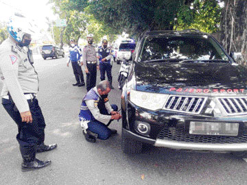 Petugas Dishub didampingi personel  Satlantas mengempeskan ban kendaraan yang tengah parkir di bibir jalan, kemarin (26/4).