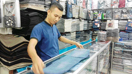 Salah seorang pegawai toko pakaian di Pasar Raya sedang melipat celana yang akan dijual, kemarin. (IST)