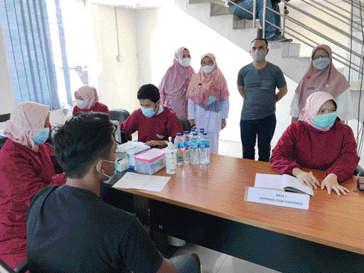 PANTAU: Direktur Padang Ekspres M Nazir Fahmi memantau pelaksanaan vaksinasi massal diikuti karyawan beserta keluarganya di Gedung Graha Pena Padang, kemarin (7/7).(Sy Ridwan/Padek)