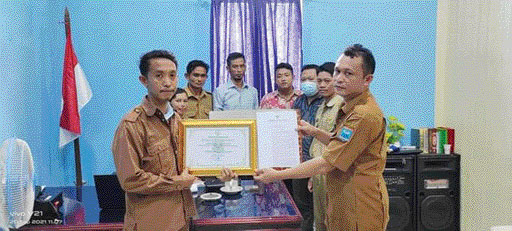 PRESTASI: Kepala Desa Muara Sikabaluan, Afrijon (kanan) menerima piagam penghargaan desa berprestasi yang diserahkan salah seorang pegawai di Dinas DPMP2KB Kepulauan Mentawai.(IST)