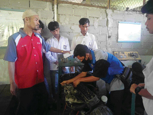 PENUH SEMANGAT: Siswa Kelas XI Jurusan TKR terlihat serius mengikuti bimbingan praktik bersama guru pembimbing di ruang workshop.(YONI SYAFRIZAL/PADEK)