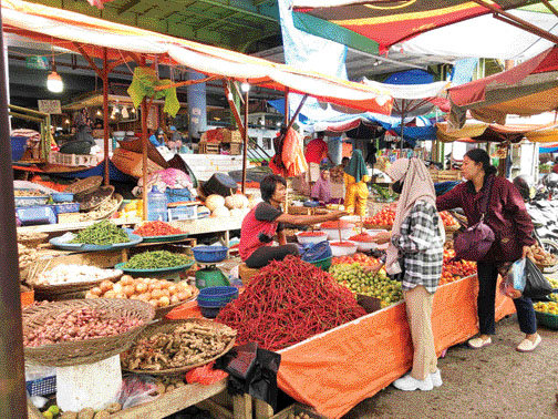 LAYANI PEMBELI: Pedagang sembako di Pasar Raya Padang sedang melayani pembeli.(DEWI/PADEK)