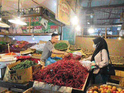 MEROKET: Seorang pedagang kebutuhan pokok di Pasar Raya Padang sedang melayani pembeli.(DEWI/PADEK)