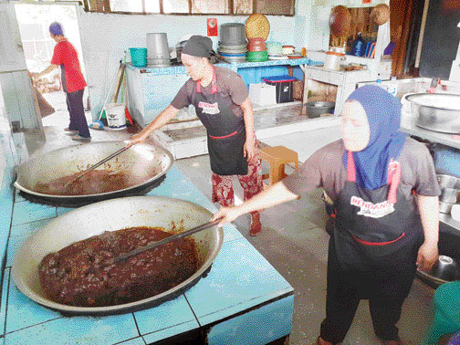 TEMBUS MANCANEGARA: Dua pekerja terlihat sedang memasak Rendang Uni Lili. Sekarang, rendang yang diproduksi di Solsel ini sangat diminati di pasaran Asia, Eropa serta Amerika.(ARDI/PADEK)