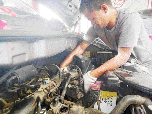 GIGIH: Amrizal, sang Owner Amri Motor tetap turun tangan memperbaiki mobil pelanggannya, meski banyak memiliki karyawan.(ARFIDEL ILHAM/PADEK)