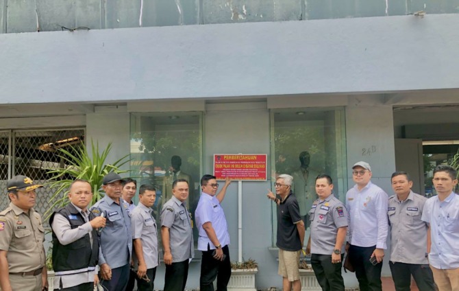 PASANG PALANG PERINGATAN: Kepala Bapenda Padang Yosefriawan bersama tim memasang palang peringatan menunggak pajak di salah satu WP di Kota Padang, kemarin (24/8).