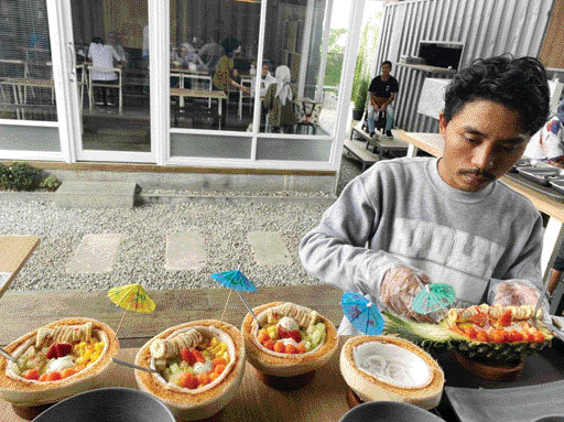 GUGAH SELERA: Salah satu karyawan Alooha Tropical sedang membuat aneka es krim buah dengan wadah batok kelapa dan kulit nenas.(IST)