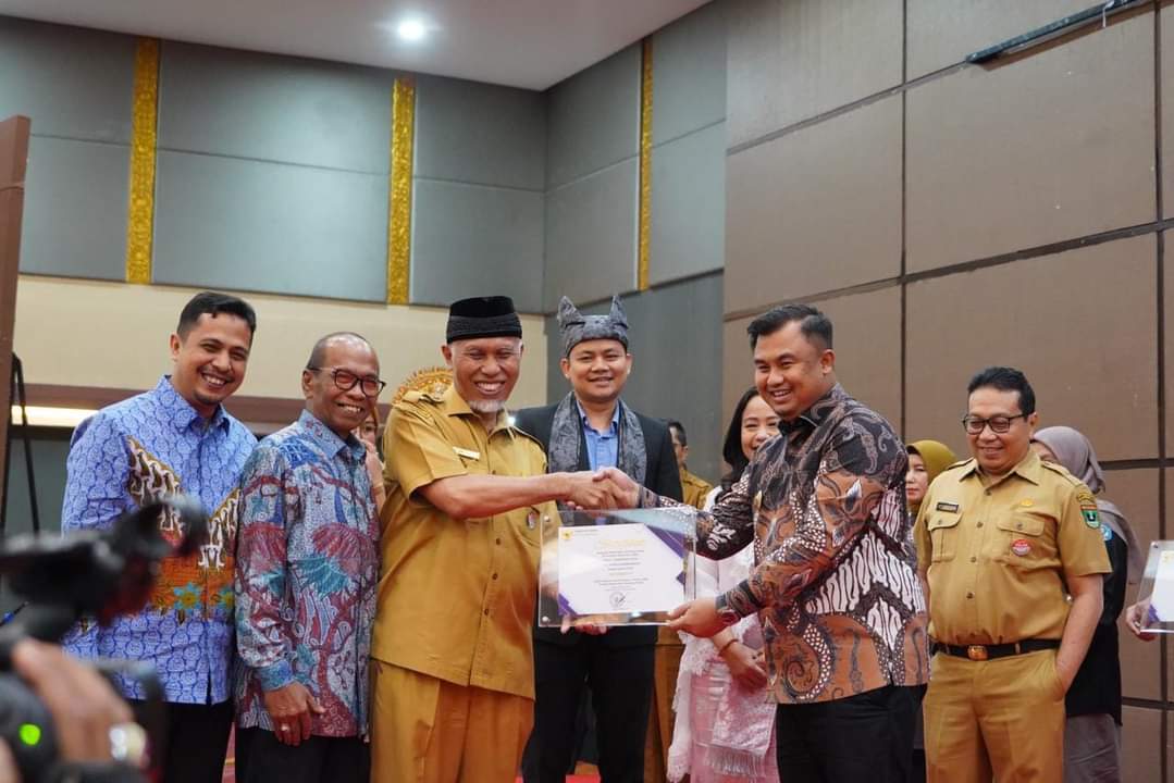 LAYANAN PUBLIK: Bupati Dharmasraya Sutan Riska Tuanku Kerajaan menerima Anugerah Keterbukaan Informasi Publik oleh Gubernur Sumbar Mahyeldi di Hotel Truntum, Padang, Senin (12/12).(IST)