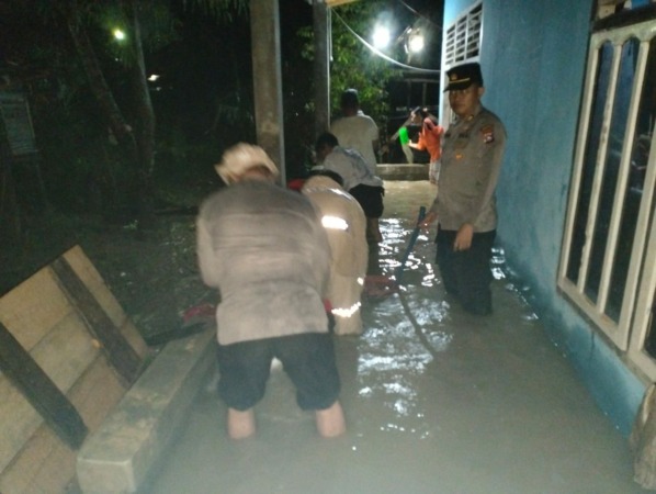 PERTOLONGAN: Kapolsek Sungairumbai, AKP Suyanto membantu menyelamatkan barang milik warga terdampak banjir di Sungairumbai, Sabtu (17/12).(IST)