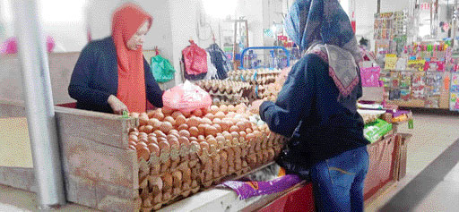 LAYANI PEMBELI: Seorang konsumen membeli telur ayam di lapak Emi, pedagang telur ayam di Pasar Raya Kota Padang, Senin (30/1).(MUHAMMAD HAFIZ/PADEK)