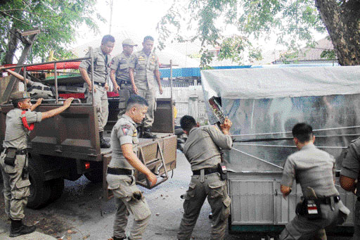 PENERTIBAN: Personel Satpol PP Kota Padang membongkar lapak PKL yang berdiri di atas trotoar di kawasan Padang Timur, kemarin.(IST)