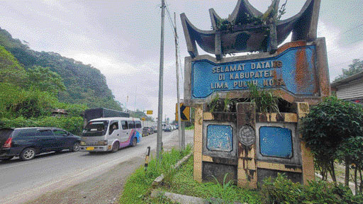 TIDAK TERAWAT: Gapura Kabupaten Limapuluh Kota yang terletak di pinggir jalan Payakumbuh-Bukittinggi, Selasa siang (14/3), terlihat bersemak dan tidak terawat. Masyarakat dan pengendara yang lewat mendorong Pemkab Limapuluh Kota mengurus tugu yang menjadi