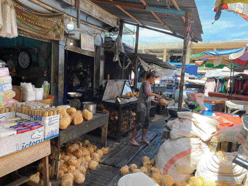 MENINGKAT: Pedagang santan dan kelapa parut, Syahrial, membelah kelapa yang ingin diparut, Kamis (23/3).(SARAH AULIA SEPTIHANA/PADEK)